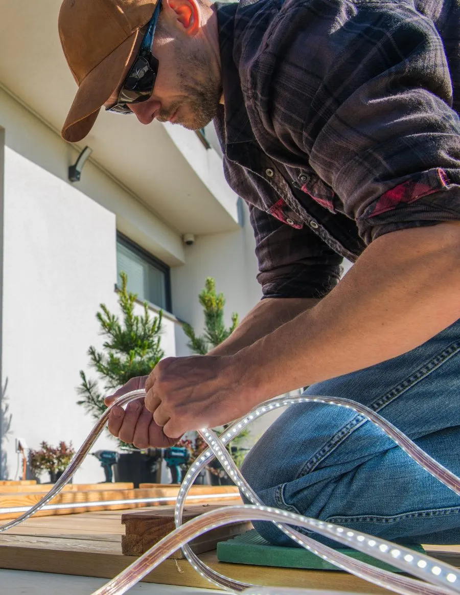 Expert technician from Dream Patios LA installing custom LED outdoor lighting on a luxury patio deck in Los Angeles.