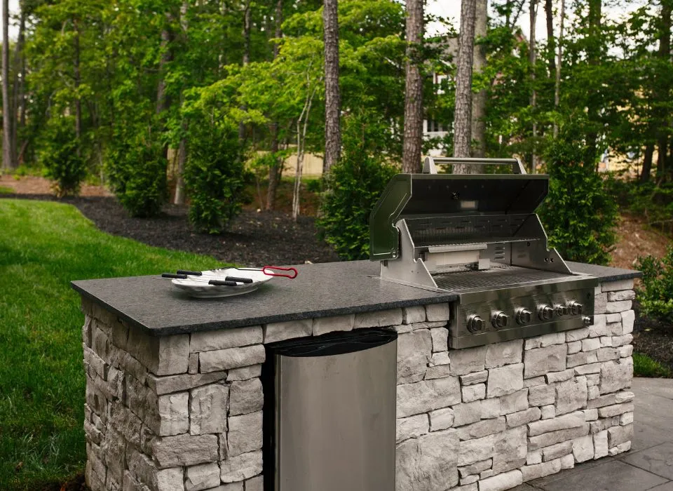Modern outdoor kitchen design featuring a sleek black pergola and professional BBQ station in a Los Angeles home by Dream Patios LA.